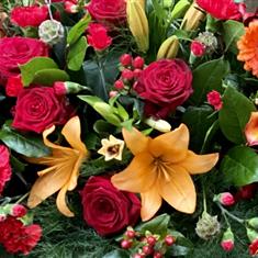 A florist choice Red and Orange casket spray