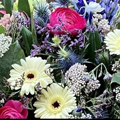 A florist choice lemon, cerise and lilac casket spray